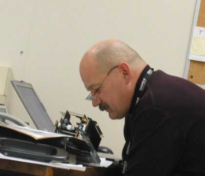 Derek listening to a printer, trying to find the mysterious beep